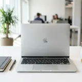 清潔な白いデスクに置かれたノートパソコン。その横には、会社名が入ったノートやペン、小さな観葉植物がセットになった「ウェルカムキット」があり、新しい仲間を迎え入れること（オンボーディング）を表現している。