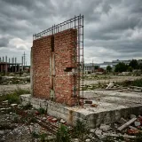 すでに取り戻せない過去の投資費用であるサンクコストを象徴する、コンクリートの土台の上に取り残された作りかけのレンガの壁の高品質な写真