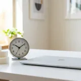清潔な白いデスクに置かれたノートパソコンと、ふわふわした白いクッションのようなオブジェ。その横には時計が置かれ、時間的なゆとり（バッファ）を表現している。